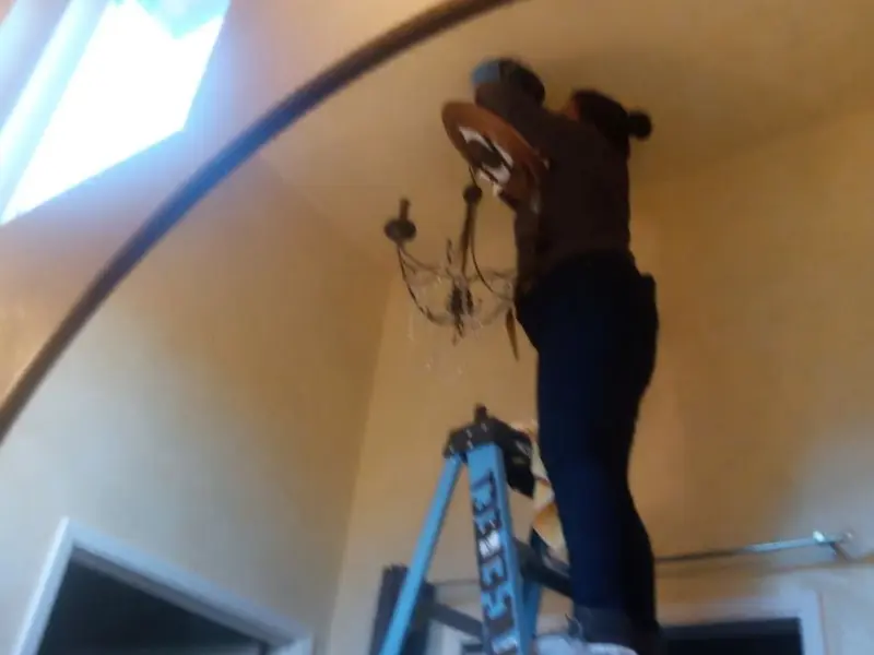 Electrician installing a chandelier in a Maynard residence
